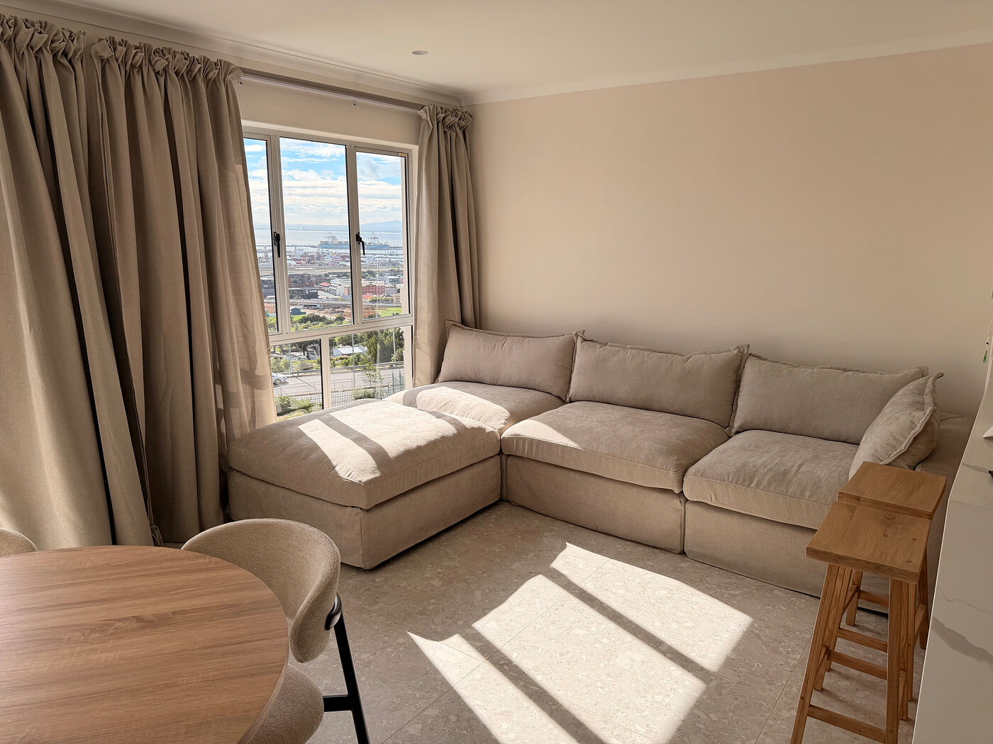 Living and dining area with a corner sofa and city views through the windows