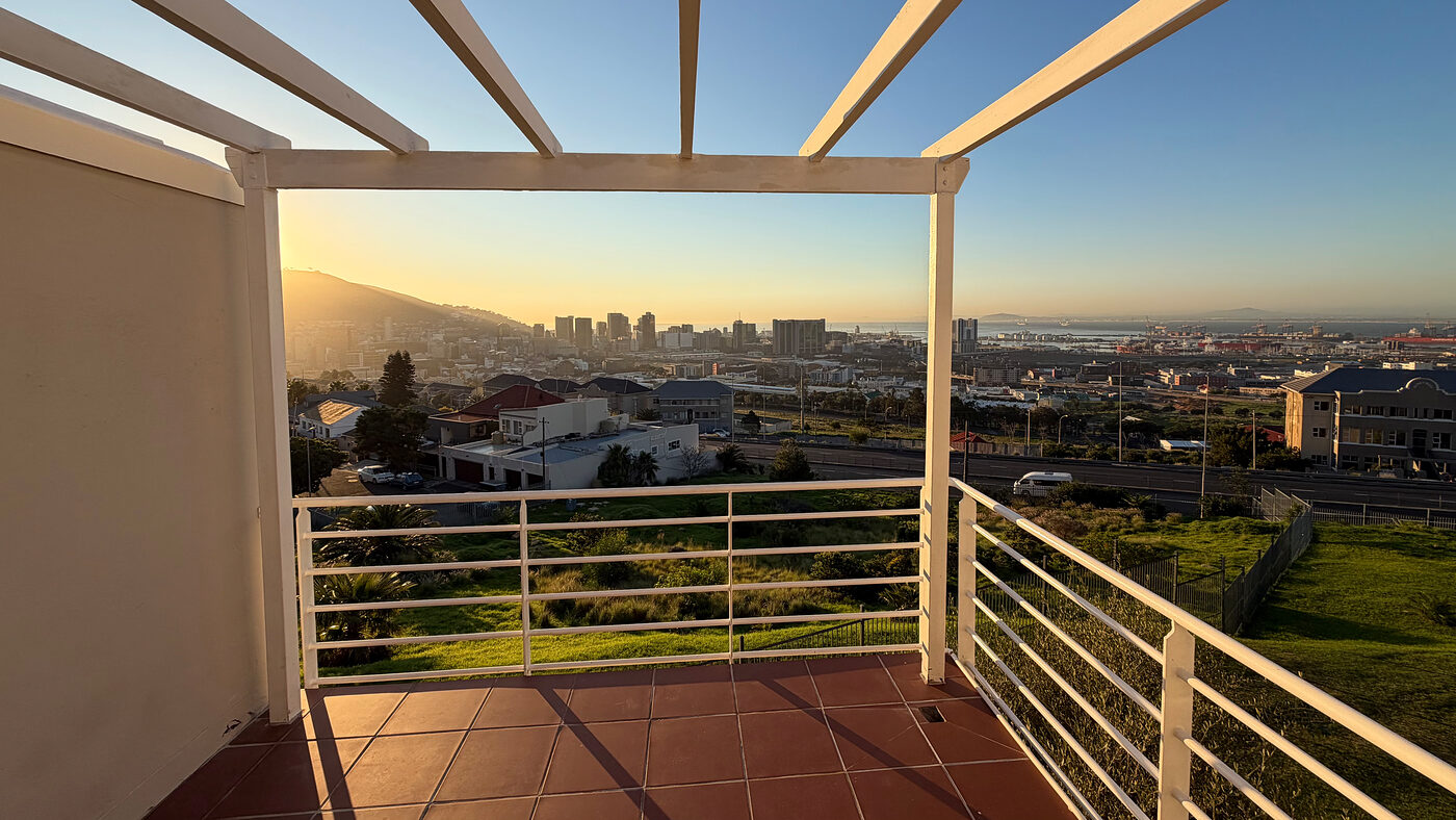 Covered balcony with a pergola looking out over Cape Town at sunset
